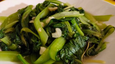 Sarımsak ve soya sosuyla pişirilmiş yeşil yapraklı Çin sebzesi..