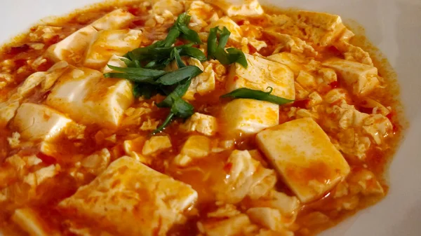 Baharatlı kırmızı biber soslu, yeşil sağlıklı soğanlı Çin mapo tofu yemeğinin detaylı görüntüsü..