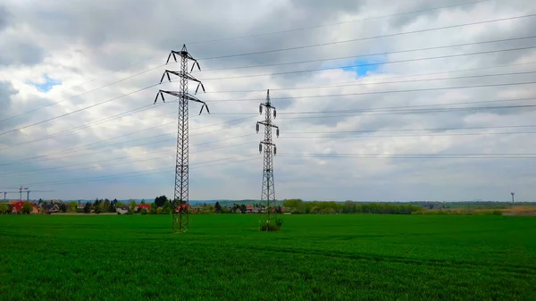 Electric distribution grid towers on green field.