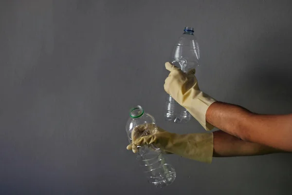 Man with gloves recycling some plastic bottles.