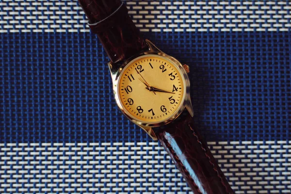 Isolated gold and quartz watch with leather strap.