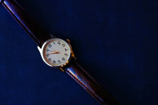 Gold and quartz watch on a black background.