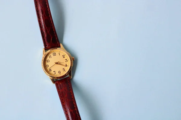 Gold and quartz watch on a blue background.