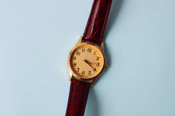 Gold and quartz watch on a blue background.