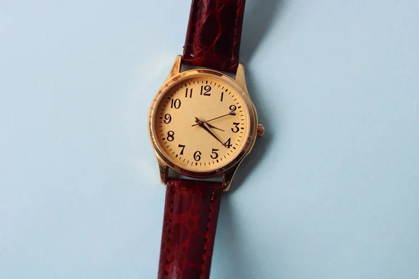 Gold and quartz watch on a blue background.