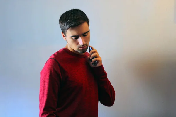 Young man using perfume or cologne on a gray background.