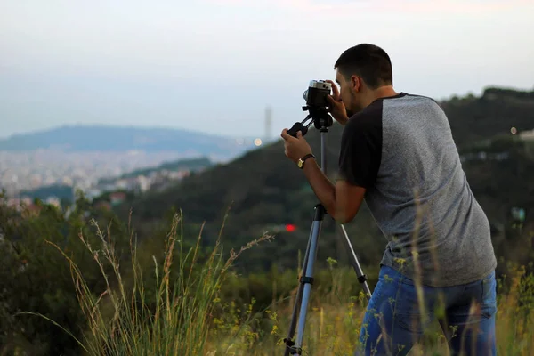 Young photographer taking some pictures with his analog camera and a tripod.