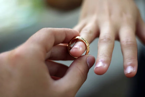 Husband putting a gold ring on his wife during the wedding.