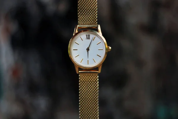 Gold watch and quartz on a brown background.