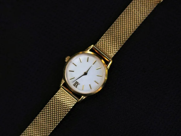 Gold watch and quartz on a black background.