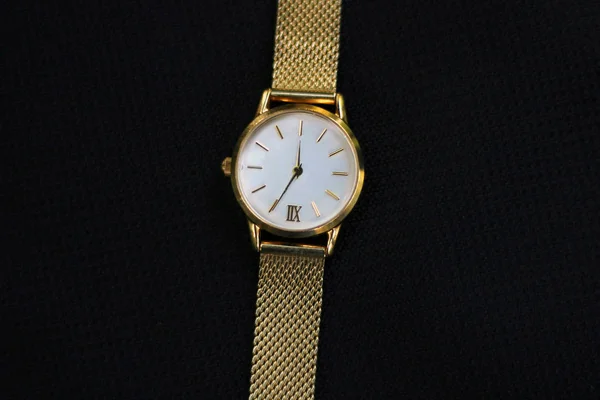 Gold watch and quartz on a black background.