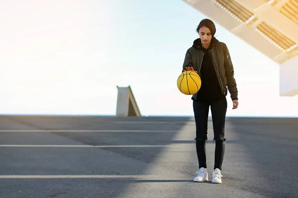 Female basketball player throwing yellow basketball in an urban court. Sport concept.