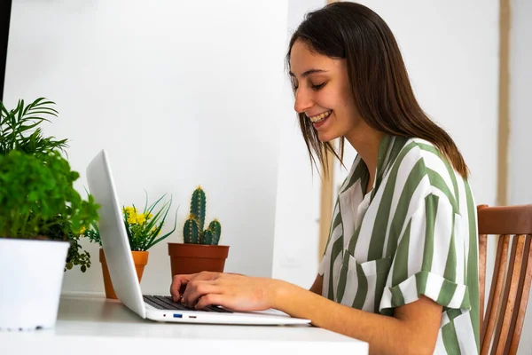 Female office worker working at home next to some plants. Concept of working with plants. Plants on the desk.
