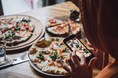 Pizza yemek cep telefonu ile fotoğraf çekici.