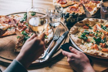 Çeşitli pizzalar ve bardak şarap akşam yemeği için bir restoranda servis.