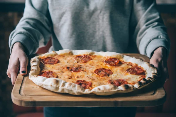 Mãos Segurar Uma Tábua Com Pepperoni Pizza Imagem Tonificada — Fotografia de Stock