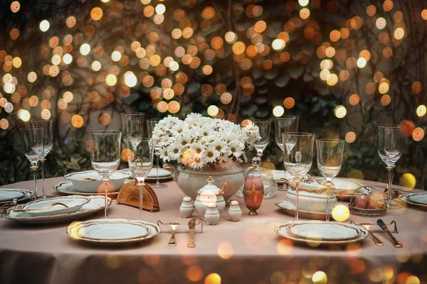 Table served for luxury dinner party lighted with garlands