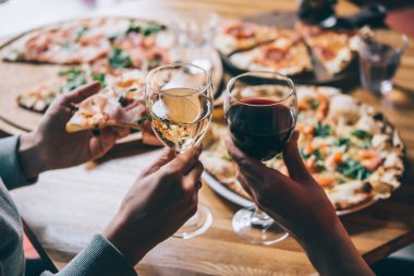 Çeşitli pizzalar ve bardak şarap akşam yemeği için bir restoranda servis.