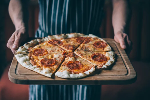 Mãos Segurar Uma Tábua Com Pepperoni Pizza Imagem Tonificada — Fotografia de Stock