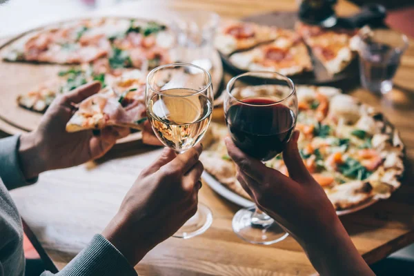 Various pizzas and glasses of wine served for dinner in a restaurant.