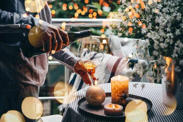 Girl pouring wine on a terrace. Cozy evening and relax concept