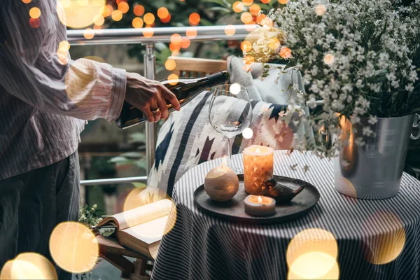 Girl pouring wine on a terrace. Cozy evening and relax concept