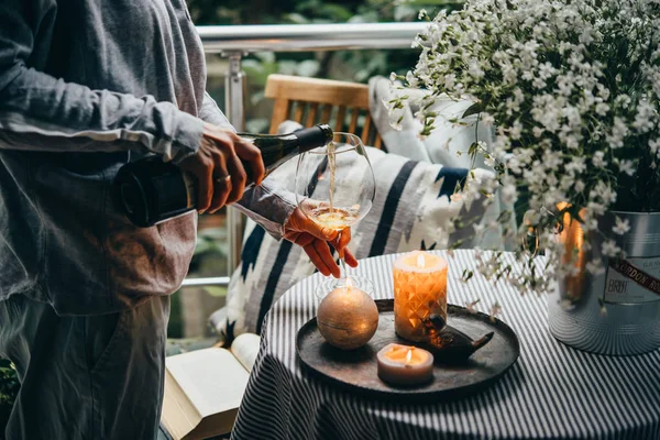 Girl pouring wine on a terrace. Cozy evening and relax concept