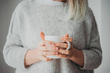 Elinde kahve ya da çay tutan bir kız.