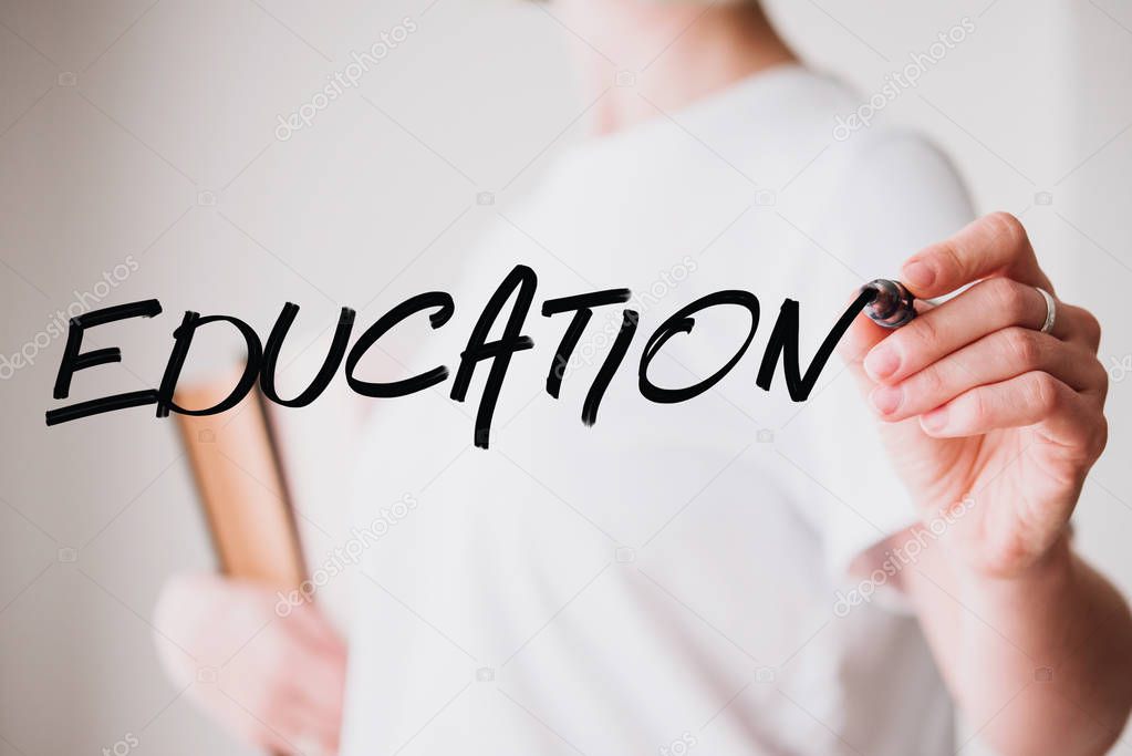 Writing hand. Woman holds pen or marker and writing Education word