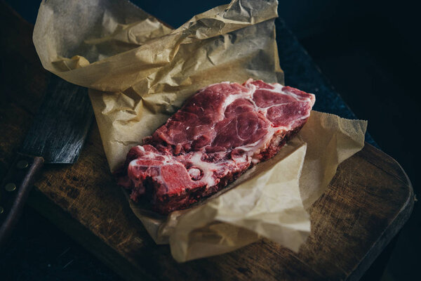 A cut piece of blade pork steak on a wooden board.