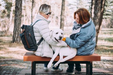 A köpek ile oturan mutlu lezbiyen çift
