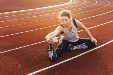 Genç, güzel bir kadın selfie bir stadyum koşu parkuru oturan yapma.