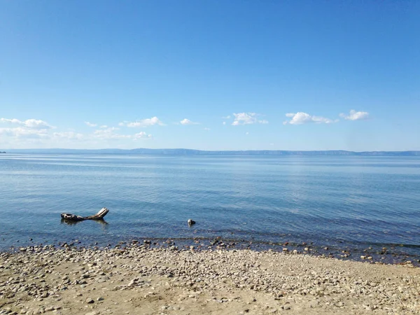 Lago Baikal, la extensión azul de agua y pequeñas piedras en la orilla, un paisaje tranquilo — Foto de Stock