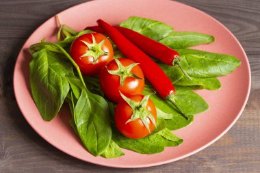 Olgun domates, ıspanak ve bambu tabağıüzerinde acı kırmızı biber. Yemek pişirmek için yenilebilir sebzeler, organik vegan vejetaryen, parlak kırmızı ve yeşil renkler