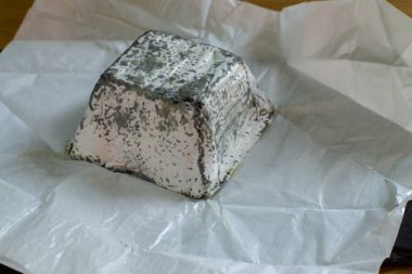 Yumuşak çiftlik peyniri küf ve kömür ile keçi sütünden yapılır. Briquette beyaz kağıt yakın çekim peynir bir parça