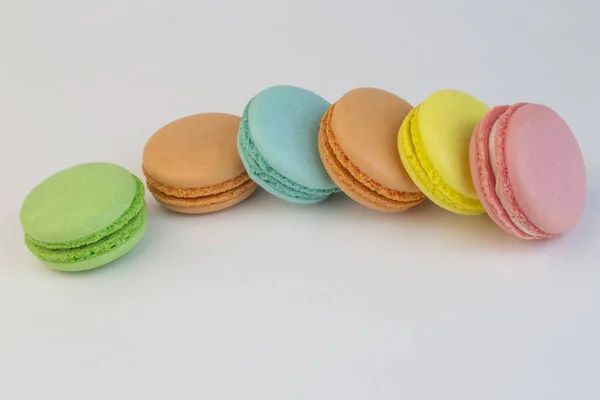 Macaroon édes biscuit, francia péksütemények, különböző színű, fehér háttér, makaróni szétszórt egy fehér asztal — Stock Fotó