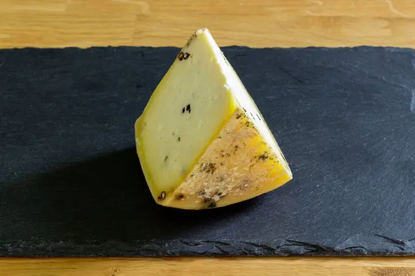 Треугольный сегмент фермерского творога с приправами и специями, кусочек сыра на черном фоне — стоковое фото