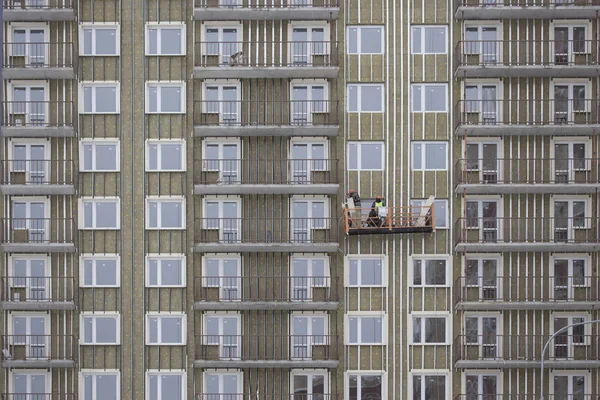 Constructor colgar en la cesta de una casa sin terminar. Construcción de un edificio residencial de apartamentos de gran altura —  Fotos de Stock