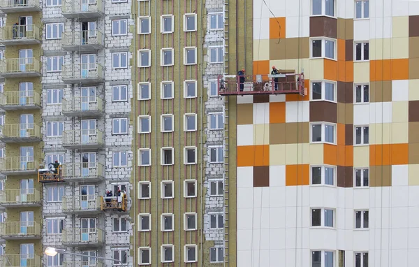 La decoración de fachada de un edificio residencial de gran altura. Trabajadores completan la decoración de la fachada mientras — Foto de Stock