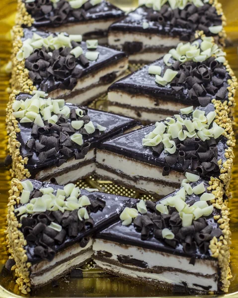 Pastel de esponja de chocolate espolvoreado con chips de chocolate blanco y negro. Trozos de pastel en la ventana de una casa de té —  Fotos de Stock