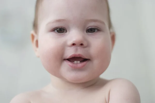Baby 6-7 hónap mosolyogva mutatja az első fogak, baba arca közeli portré. Csinos kislány fiú puffadt arca — Stock Fotó