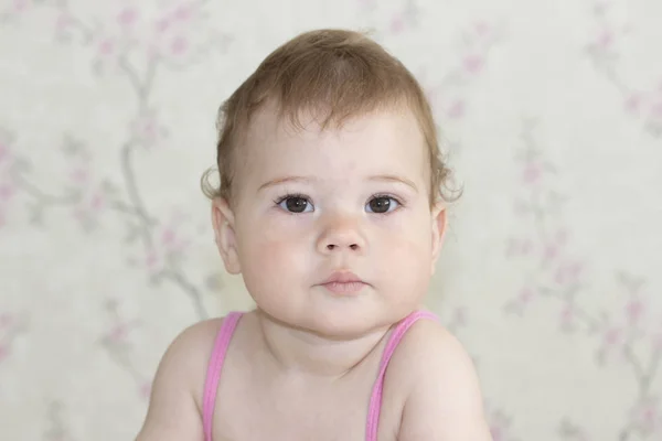 Sevimli küçük kız 10 aylık, bebek portre yakın çekim. Bebek ciddi bir yüz ile kameraya bakıyor, kahverengi gözlü bebek kız, yumuşak odak — Stok fotoğraf