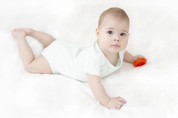 Baby girl boy is lying on his stomach in white clothes. European Caucasian child with brown eyes, top view of looking at the camera. Portrait of baby — Stock Photo, Image