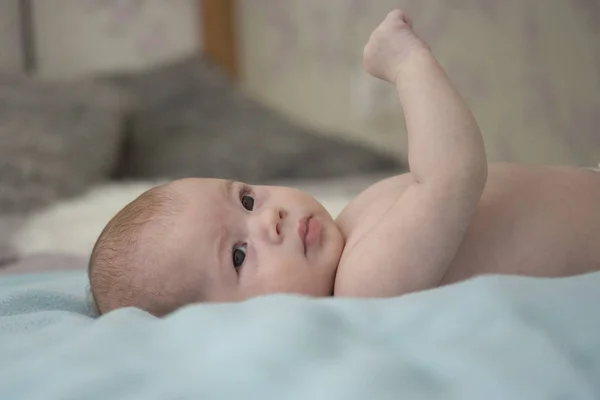 Üç aylık bebek çocuk sırt ında yatıyor. Yeni doğan bebek ellerini inceliyor. Dikey yakın çekim yumuşak odaklama — Stok fotoğraf