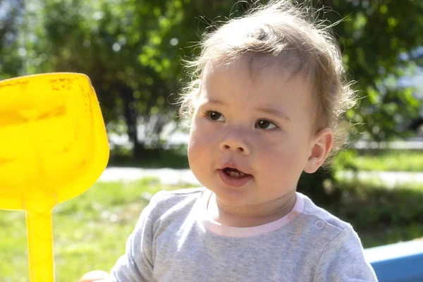 Портрет маленькой девочки-мальчика крупным планом. Ребенок с желтой пластиковой лопатой для прогулки на природе — стоковое фото