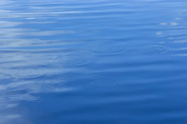 Cerchi sull'acqua, tracce di goccioline sulla superficie blu del serbatoio, uno stagno lacustre con cerchi sulla superficie dell'acqua — Foto Stock