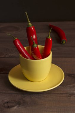 Beautiful red hot chili pepper, a few peppers in a yellow cup on a wooden table