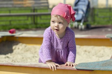 1 yaşındaki küçük bir kız çocuğu neşeyle yan tarafa bakıyor. yatay yakın plan