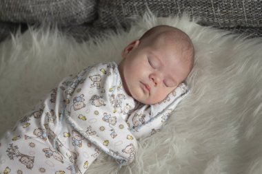 Baby 1 month sleeps on fur plaid. Portrait of a sleeping newborn baby girl boy soft focus clipart