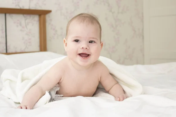 Baby 6 maanden lachend liggend onder een handdoek. Baby na het zwemmen. Mooi schattig gezicht baby jongen meisje, zachte focus — Stockfoto